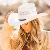 Woman wearing a white cowboy hat with a blurred natural background